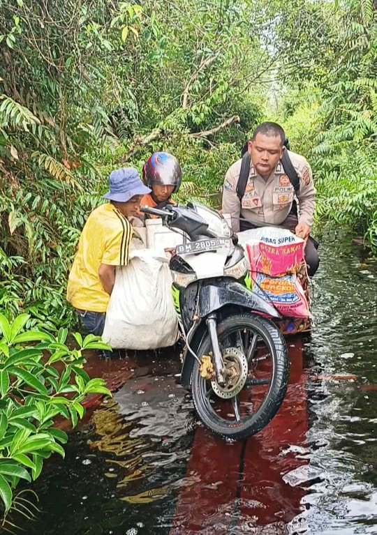 Bhabinkamtibmas di Tebingtinggi Timur Ini Bantu Warga Melintasi Jalan Terendam Banjir